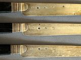 six knives are lined up on a table with a white cloth