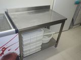 une table de travail en acier inoxydable équipée d'un évier et d'un congélateur