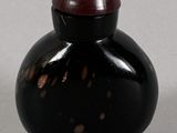 a small black vase with a red lid on a table