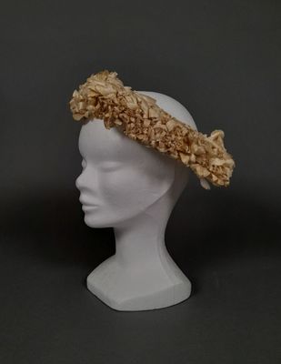 une tête de mannequin blanche coiffée d'un chapeau à fleurs