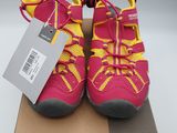 a pair of pink and yellow shoes on a cardboard box