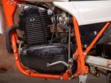 a close up of an orange and white motorcycle parked in a garage