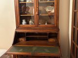 a wooden desk with a glass front cabinet in a room