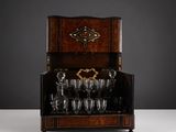 un ancien meuble à alcool en bois sur lequel sont posés des verres à vin
