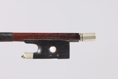 un gros plan d'un archet de violon posé sur une surface blanche