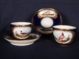 trois tasses et soucoupes ornées d'oiseaux, posées sur une table