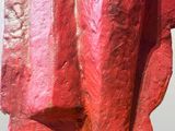 a red sculpture of a man sitting on top of a rock