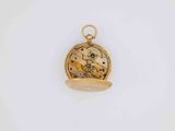 a close up of a gold pocket watch on a white surface