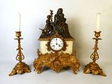 trois bougies et une horloge posées sur une table