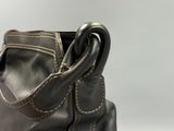 someone is holding a black purse with two handles on a white surface