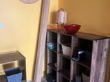 a wooden shelf with a bowl on top of it in the corner of a room