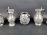 several silver vases and pitchers are lined up on a table