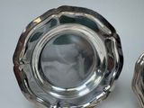 two silver plates sitting on a white table