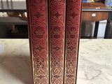 three red books sitting on top of a marble counter top