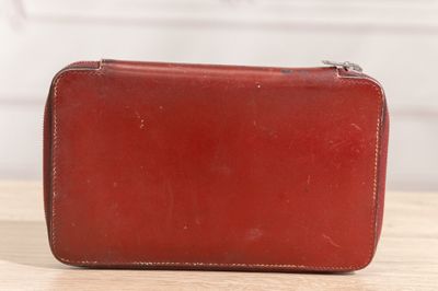 an old red leather purse sitting on top of a wooden table