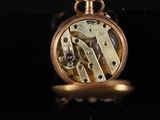 a close up of a pocket watch on a black surface