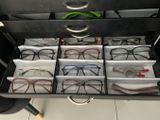 many pairs of glasses sitting in a drawer on a desk