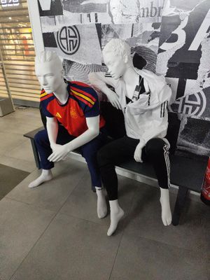 deux mannequins assis sur un banc devant un mur