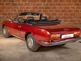 a red convertible car parked in front of a brick wall