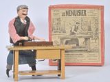 a figurine of a man sitting at a desk in front of a newspaper