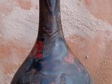 un vase noir posé par terre près d'un mur
