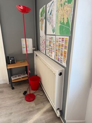 a red floor lamp sitting next to a radiator in a room
