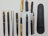 various pens and pencils laid out on a white surface