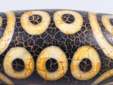 a close up of a black and gold bead on a white surface
