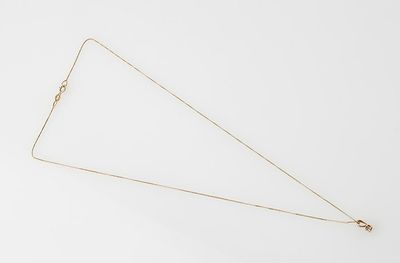 a close up of a gold necklace on a white surface