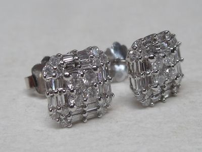 a pair of diamond stud earrings sitting on a table