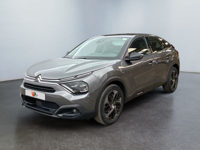 La voiture grise est garée dans une grande pièce au sol noir.