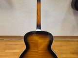 an acoustic guitar sitting on top of a hard wood floor