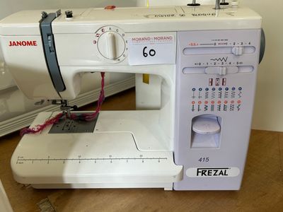 a white sewing machine sitting on a table next to a sewing machine