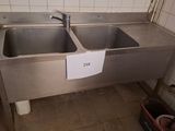 two sinks in a public restroom with a sign on the wall