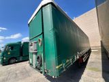 two green semi trucks parked next to each other in a parking lot