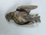 a bronze bird that is sitting on a white surface