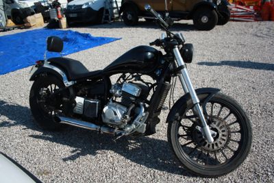une moto noire garée sur un parking à côté d'une voiture