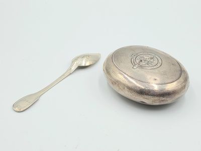 assiette en argent avec une cuillère et un repose-cuillère posés sur un fond blanc