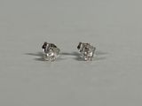 a pair of diamond stud earrings sitting on top of a table
