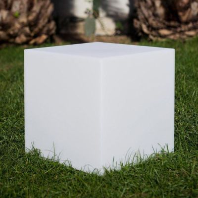 un cube blanc dans l'herbe, avec des palmiers en arrière-plan