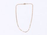 a gold chain necklace with a small white bead on a white background