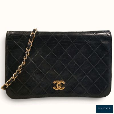 un sac à main Chanel noir auquel est suspendue une chaîne dorée