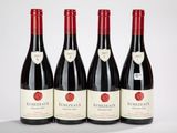 quatre bouteilles de vin rouge sont alignées sur une table