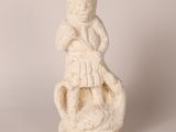 statue of a woman sitting on a rock with her arms crossed