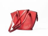 red louis vuitton bucket bag with strap on white background
