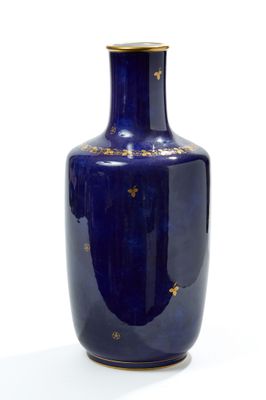 a blue vase with gold stars on it on a white surface