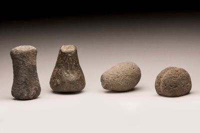 Plusieurs pierres de tailles différentes sont disposées en rangée sur une surface blanche.