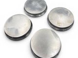 four metal buttons on a white surface with a white background