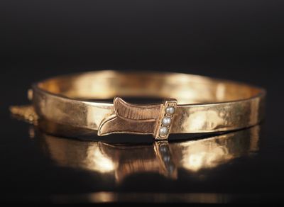 a close up of a gold bracelet with a bow on it