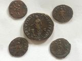 five ancient roman coins are shown on a white surface